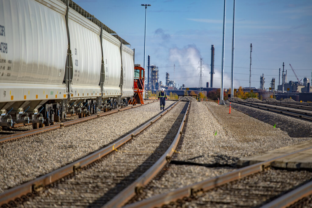 Engineer walking towards camera beside a train and rail cars